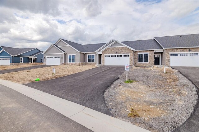view of front of property with a garage, stone siding, and aphalt driveway