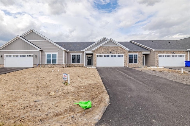 view of front facade with an attached garage, aphalt driveway, board and batten siding, and stone siding