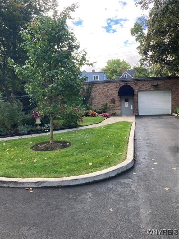 731 W Fry Unit 7G, Buffalo, NY 14222 - view of front facade with an attached garage, aphalt driveway, brick siding, and a front yard