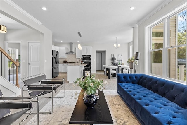 living area featuring light wood-type flooring, recessed lighting, crown molding, and stairway