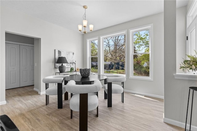 dining space featuring an inviting chandelier, baseboards, and light wood-type flooring