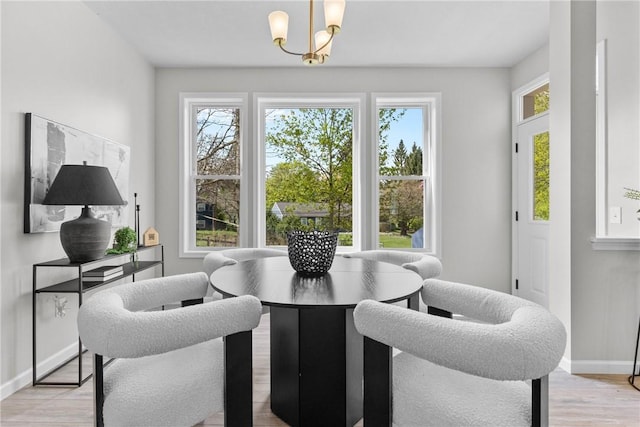 dining space featuring baseboards, an inviting chandelier, and light wood-style floors
