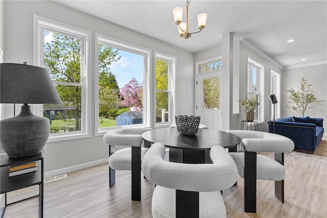 dining area featuring visible vents, crown molding, light wood-type flooring, baseboards, and a notable chandelier