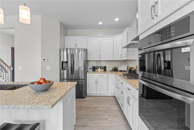 kitchen with light wood-style flooring, white cabinetry, appliances with stainless steel finishes, and backsplash