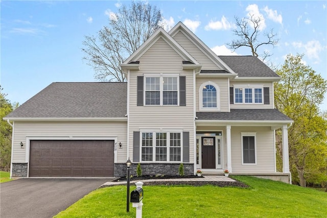 traditional-style house featuring a shingled roof, an attached garage, a front lawn, stone siding, and driveway