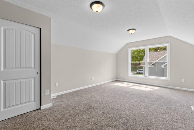 bonus room with carpet floors, a textured ceiling, baseboards, and lofted ceiling