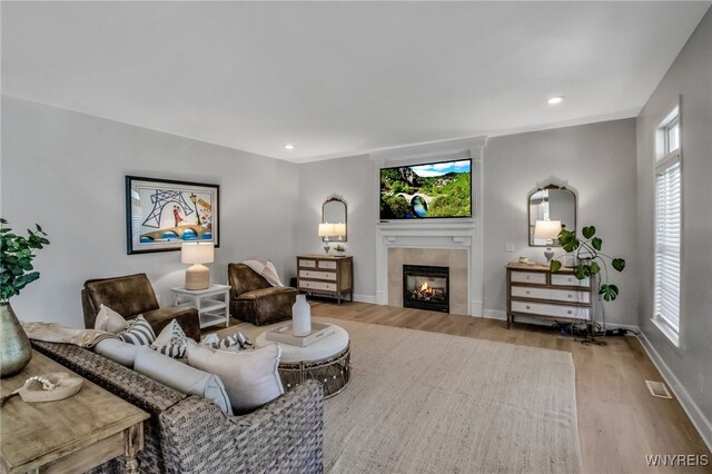 living area featuring recessed lighting, baseboards, wood finished floors, a tile fireplace, and visible vents