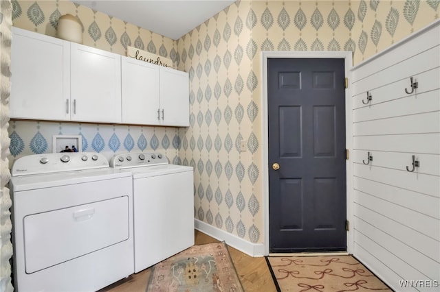laundry area featuring wood finished floors, cabinet space, baseboards, wallpapered walls, and washer and dryer