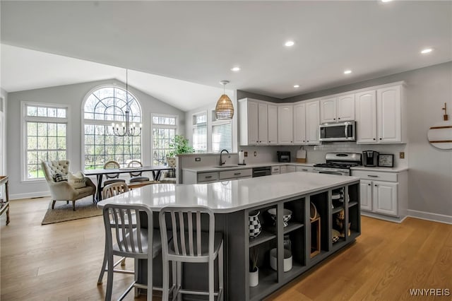 kitchen featuring a center island, open shelves, light countertops, light wood-style floors, and stainless steel appliances
