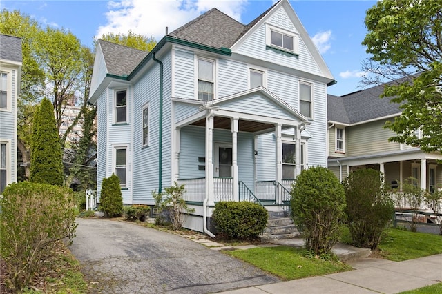 victorian house featuring a shingled roof and covered porch