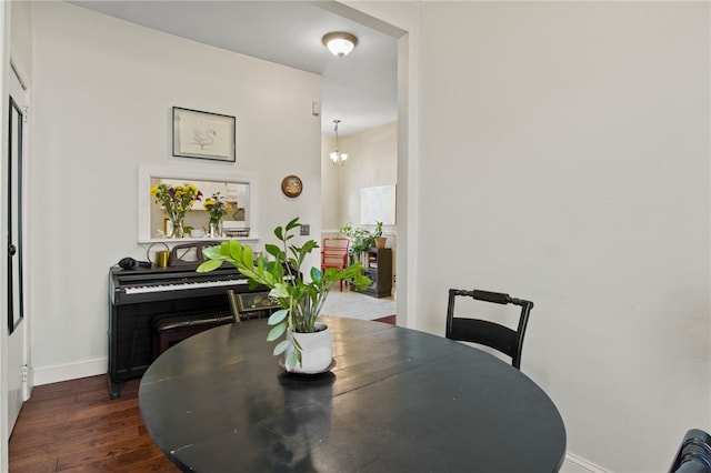 dining area featuring baseboards, dark wood-style flooring, and a notable chandelier