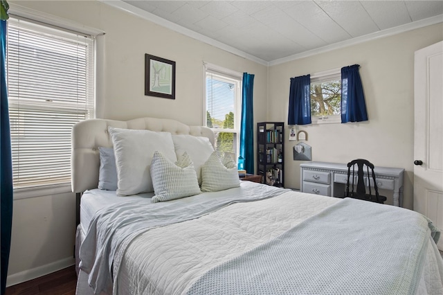 bedroom with crown molding, baseboards, wood finished floors, and multiple windows