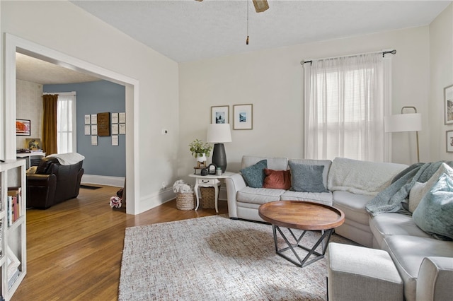 living area featuring a ceiling fan, baseboards, and wood finished floors
