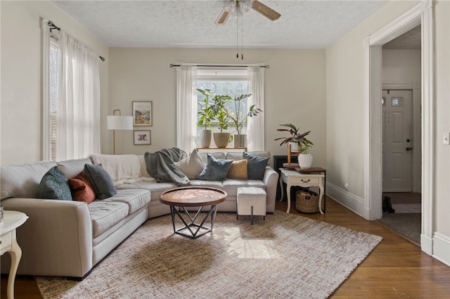 living room with a textured ceiling, baseboards, a ceiling fan, and wood finished floors