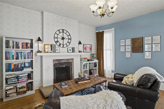 living area featuring a textured ceiling, wood finished floors, a chandelier, and a fireplace