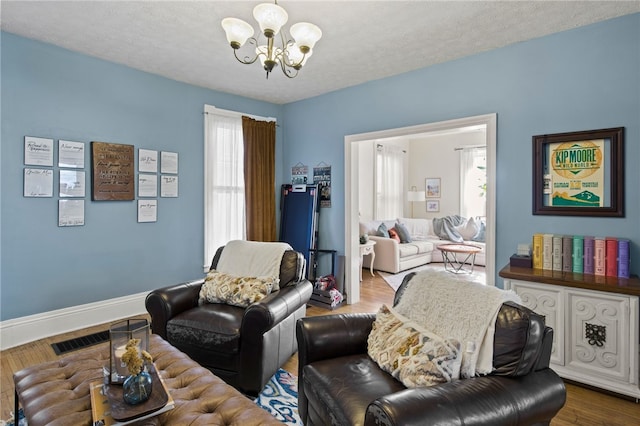 living area featuring visible vents, baseboards, dark wood-type flooring, a textured ceiling, and a notable chandelier