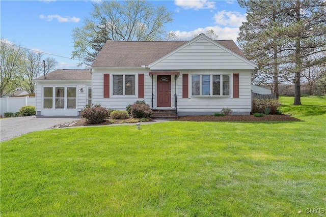view of front of home featuring a shingled roof, a front lawn, and fence