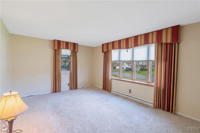 empty room featuring carpet floors, baseboards, a baseboard heating unit, and a wealth of natural light