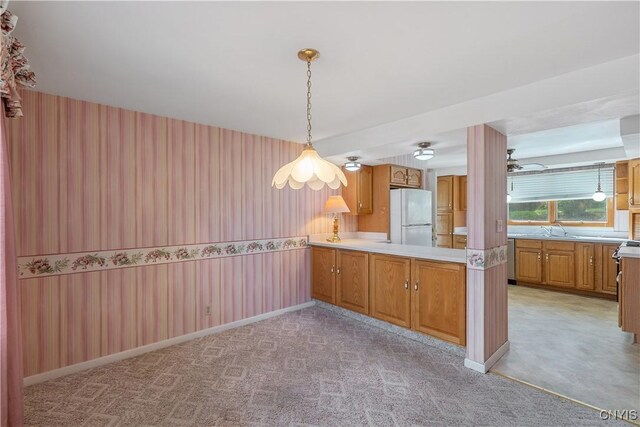 kitchen with light countertops, freestanding refrigerator, a peninsula, and wallpapered walls