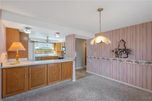 kitchen featuring light carpet, a sink, brown cabinetry, wallpapered walls, and gas range