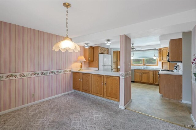 kitchen with freestanding refrigerator, brown cabinets, wallpapered walls, and light countertops