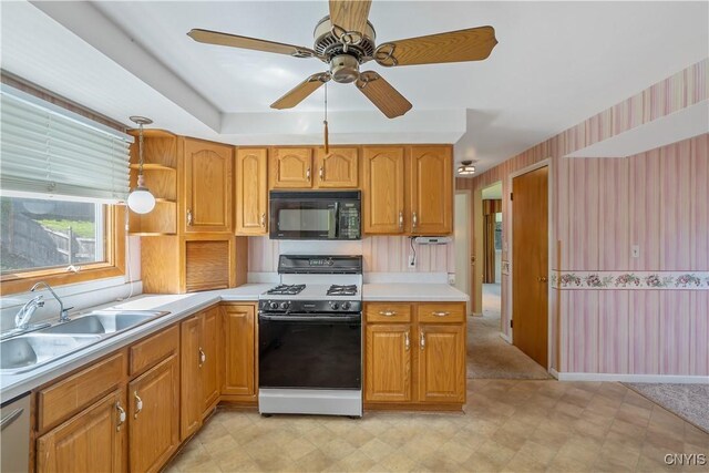 kitchen with a ceiling fan, black microwave, light countertops, range with gas cooktop, and a sink
