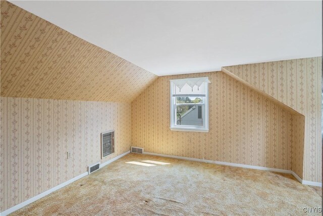 additional living space with lofted ceiling, carpet flooring, and visible vents