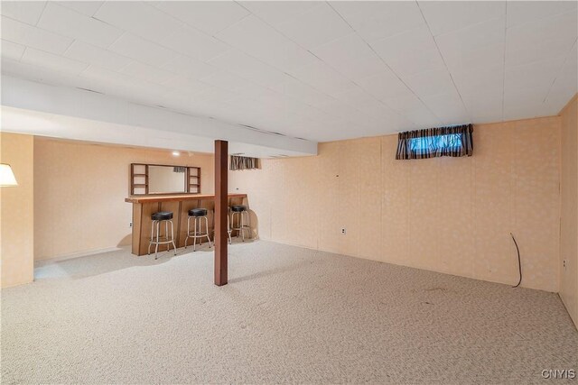 finished below grade area featuring a dry bar, carpet, and wood walls