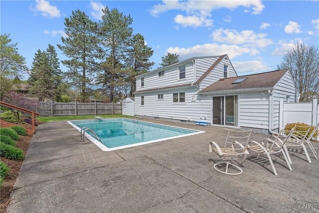 view of swimming pool featuring a fenced backyard, an outdoor structure, a patio area, and a shed