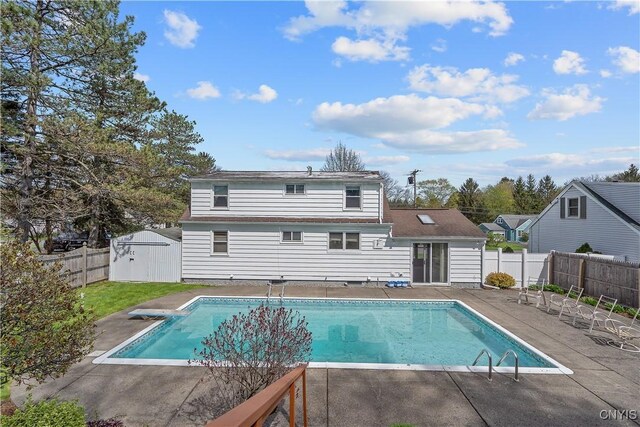 back of house with an outbuilding, a patio area, a fenced in pool, a fenced backyard, and a shed