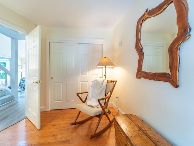 living area featuring baseboards, light wood-style flooring, and stairway