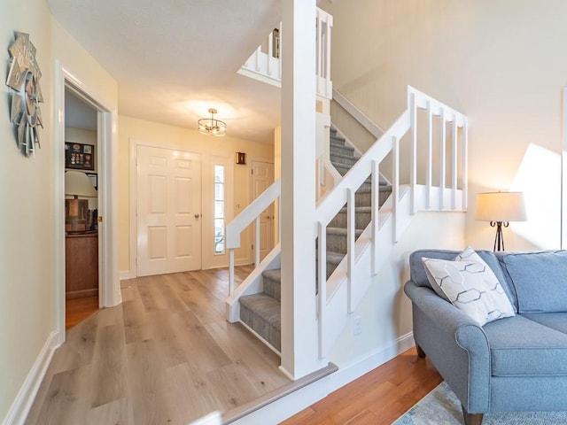 stairway with an inviting chandelier, baseboards, and wood finished floors