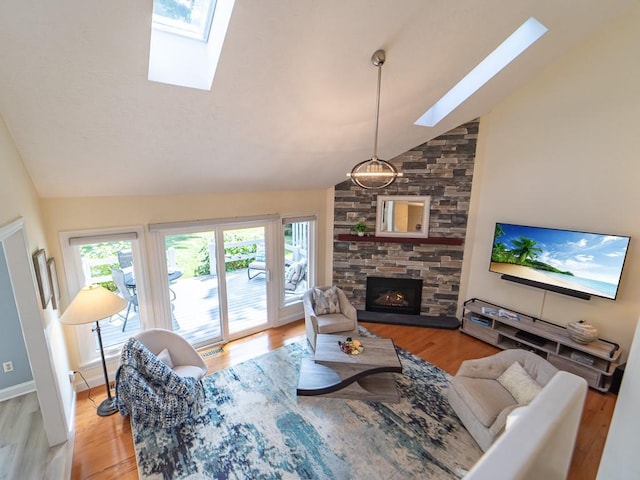 living area with a stone fireplace, light wood finished floors, and a skylight