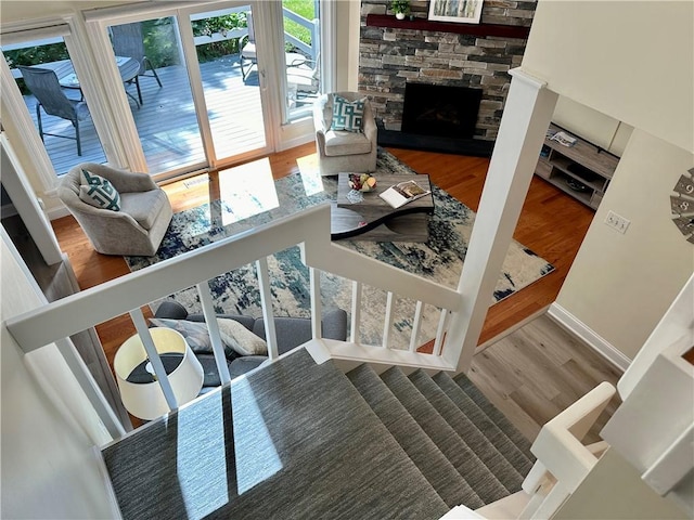 living room featuring a stone fireplace, baseboards, and wood finished floors