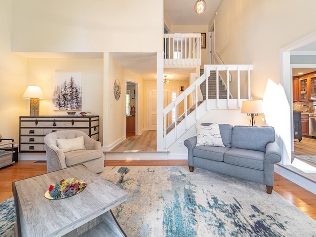 living area with baseboards, stairs, and wood finished floors