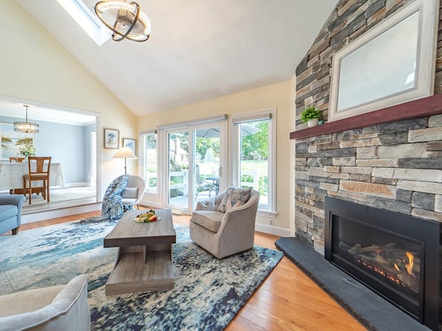 living room with high vaulted ceiling, a chandelier, wood finished floors, and a fireplace