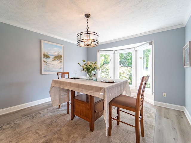 dining room featuring an inviting chandelier, baseboards, crown molding, and light wood-type flooring