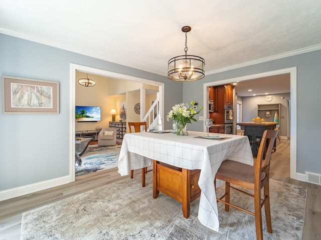 dining space with visible vents, light wood finished floors, crown molding, and a chandelier