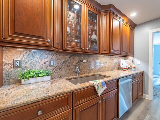 bar with light wood-style floors, baseboards, tasteful backsplash, a sink, and dishwasher