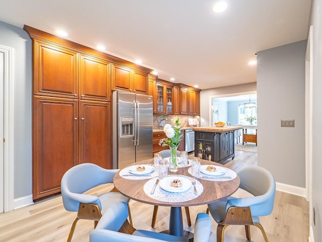 dining space with recessed lighting, baseboards, light wood finished floors, and a notable chandelier