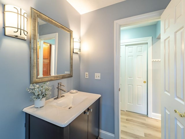 bathroom with baseboards, wood finished floors, and vanity