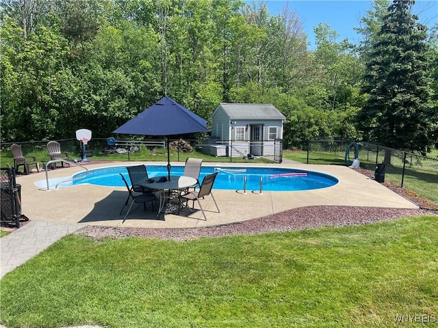 view of swimming pool featuring a patio, fence, a lawn, an outbuilding, and a fenced in pool