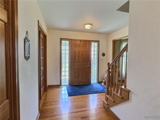 entrance foyer with baseboards, stairs, and light wood finished floors
