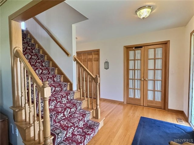 foyer with stairway, french doors, visible vents, and wood finished floors