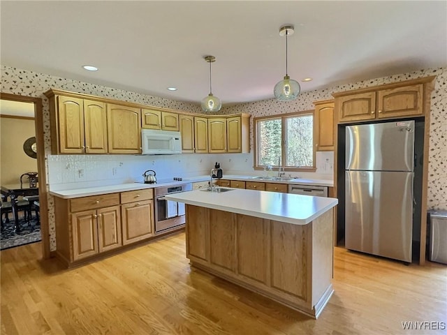 kitchen featuring a sink, light wood-style flooring, light countertops, and appliances with stainless steel finishes