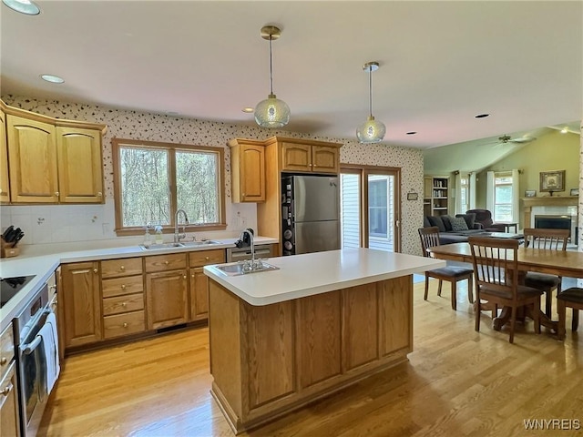 kitchen with light wood-style flooring, a sink, open floor plan, a kitchen island with sink, and appliances with stainless steel finishes