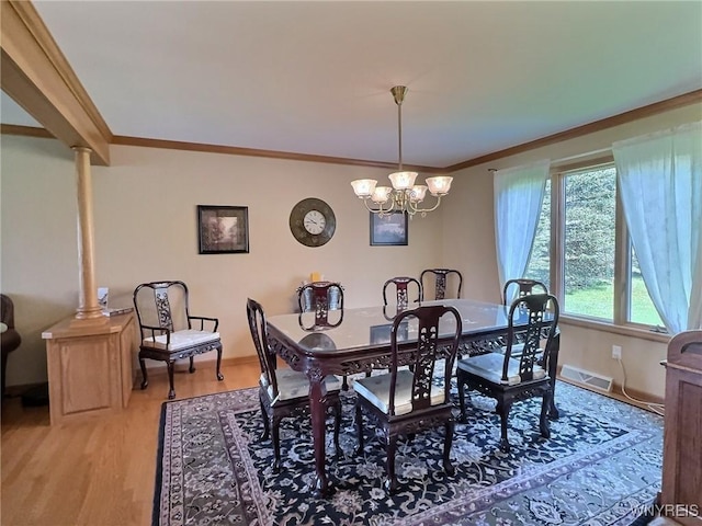 dining room with an inviting chandelier, visible vents, light wood-style flooring, and ornamental molding