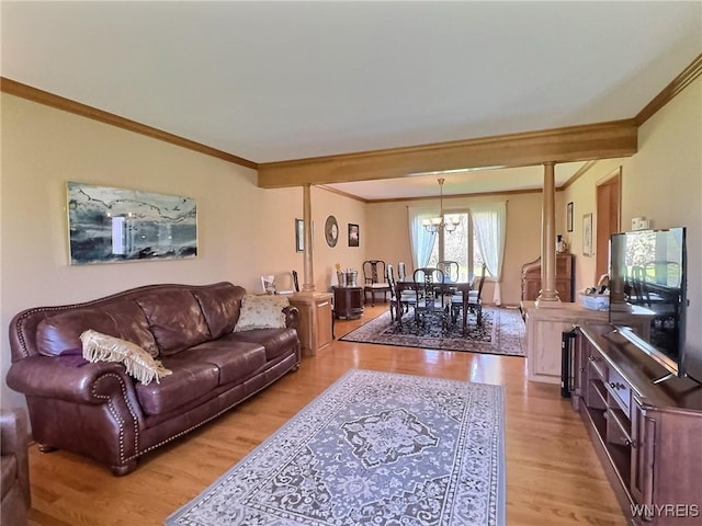 living area with light wood-style floors, a chandelier, and ornamental molding
