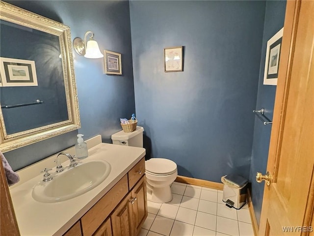 half bathroom featuring tile patterned floors, toilet, baseboards, and vanity