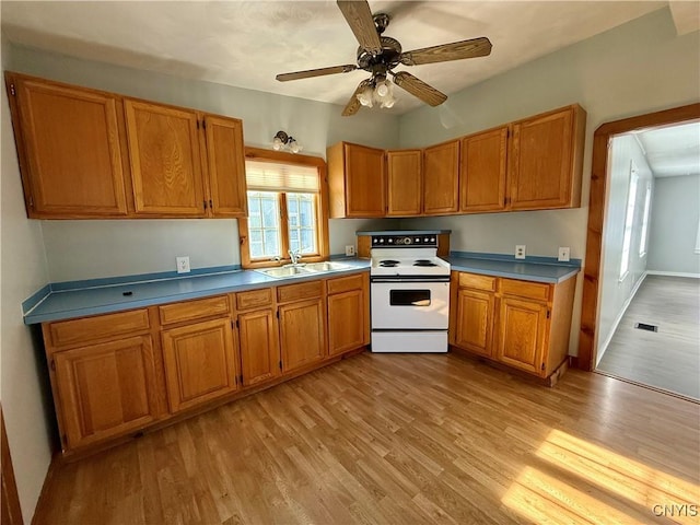 kitchen with brown cabinetry, white electric stove, a sink, and light wood finished floors